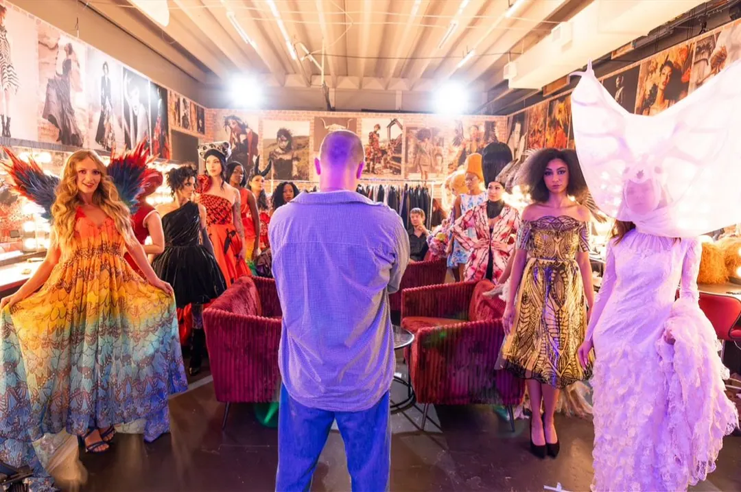 Backstage lineup of models in gowns, feathered wings and a veiled headpiece